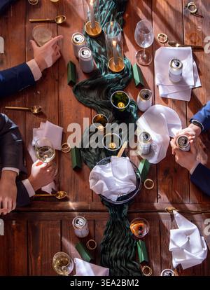 Detailreiche Aufnahme eines Tisches bei einem formellen Empfang mit Gläsern, Kerzen und Bier mit Händen. Logos wurden entfernt. Stockfoto