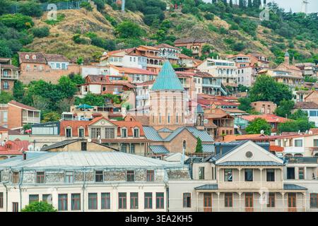 Skyline der Altstadt von Tiflis mit historischer Kirche und farbenfrohen Häusern am Hügel, Georgia. Georgianisches Wahrzeichen, das Architektur, Kultur und urbanes miteinander verbindet Stockfoto
