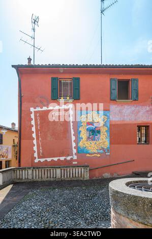 Italien, 10. April 2026: Farbenfrohe Wandmalereien schmücken das mittelalterliche Dorf Dozza, mit der historischen Festung Rocca mit Blick auf die bezaubernden Gassen. Stockfoto
