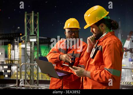 Das Ingenieurteam der Offshore-Seeplattform arbeitet zusammen, um die Extraktionseffizienz während des 24-Stunden-Betriebs zu analysieren. Bohrkähne, die Schiffsmanagementsysteme spät in der Nacht konfigurieren Stockfoto