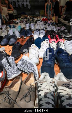 Verschiedene Turnschuhe und Schuhe werden an einem Straßenmarkt ausgestellt. Rom, Italien - 19. April 2026: Eine Nahaufnahme eines Schuhstandes auf dem Flohmarkt Porta Portese. Mehrere Paar Sneakers und Freizeitschuhe sind ordentlich auf Metallregalen und weißen Tischen angeordnet. Ein großes gelbes Preisschild ist an der Metallstruktur des Stalls unter dem hellen Morgenlicht angebracht. Rom RM Italien Copyright: XGennaroxLeonardix Stockfoto