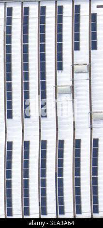 Luftaufnahme von Solarpaneelen auf einem weißen Industriedach mit Oberlichtern und vertikalen Linien in Reggello, Toskana, Italien. Stockfoto