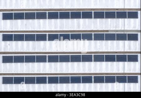 Luftaufnahme von Reihen blauer Solarpaneele auf einem weißen Wellblechdach in Reggello, Toskana, Italien. Stockfoto