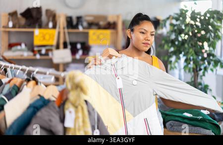 Frau wählt Mantel für die Winterzeit im modischen Bekleidungsgeschäft Stockfoto