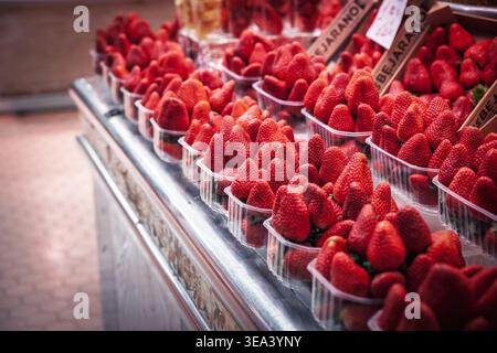 VALENCIA, SPANIEN - 7. APRIL 2025: Plastiktabletts gefüllt mit frischen Erdbeeren auf einem Markttheken in valencia. Spanien ist einer der größten Stände Stockfoto