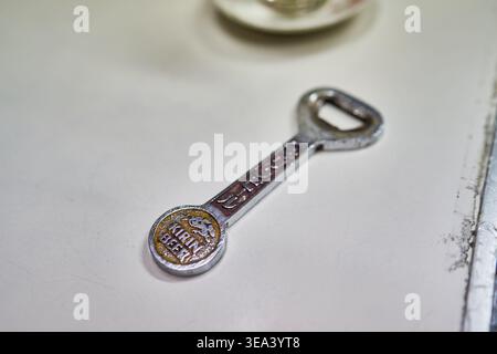 Ein Vintage-Kirin-Bier-Flaschenöffner aus Metall auf einem Tisch. Die abgenutzte, rostige Oberfläche und der japanische Text betonen eine klassische, antike Ästhetik. Stockfoto