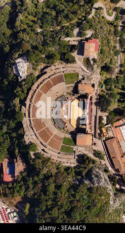 Blick aus der Vogelperspektive auf das antike Theater von Taormina mit den halbrunden Steinen und historischen Ruinen umgeben von üppiger grüner Vegetation auf einem Hi Stockfoto