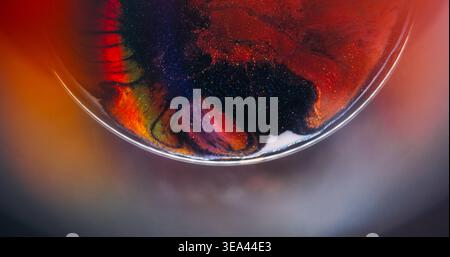 Farbenfrohe Tinte im Regenbogen. Funkelnde Flüssigkeit. Defokussierte orange blaue lila Glitzerpartikel verbreiten sich auf abstraktem, lebendigem kreativem Hintergrund. Stockfoto