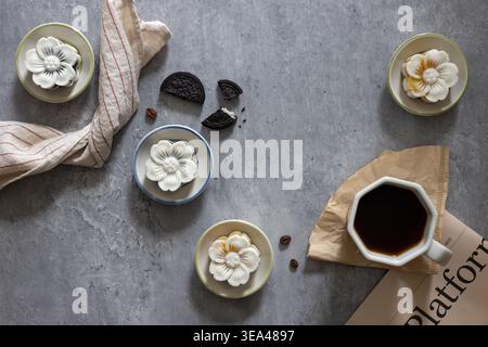 Blick von oben auf eine Tasse Kaffee, serviert mit einem chinesischen Pfannkuchen und einer Zeitung, grauer Zement im Hintergrund. Morgenkaffee. Nahaufnahme, flache Lagen. Stockfoto