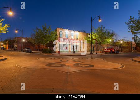 Winslow, Arizona, USA, berühmte Kreuzung mit Route 66, die in der Abenddämmerung mit historischen Gebäuden gemalt ist Stockfoto
