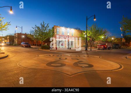 Winslow, Arizona, USA, berühmte Kreuzung mit Route 66, die in der Abenddämmerung mit historischen Gebäuden gemalt ist Stockfoto