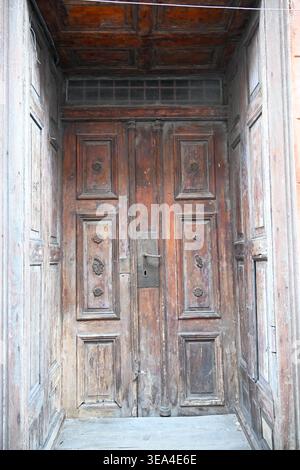 Alte schwere verwitterte Holztüren in kunstvoll verzierten Rahmen-Close-up architektonischen Details Stockfoto