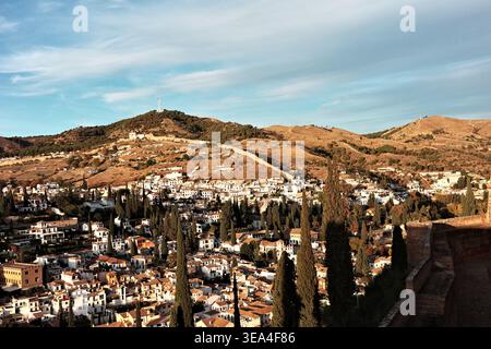 Panoramablick über das Viertel Albaicin mit weiß getünchten Häusern, Zypressen und Terrakotta-Dächern in Richtung trockener Hügel dahinter, von Alcazaba aus gesehen Stockfoto