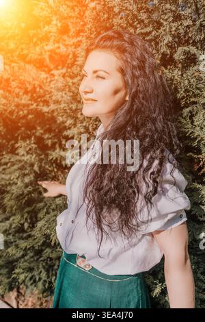 Frauenhaare stehen bei üppigen immergrünen Bäumen während einer goldenen Stunde Sonnenuntergang Stockfoto