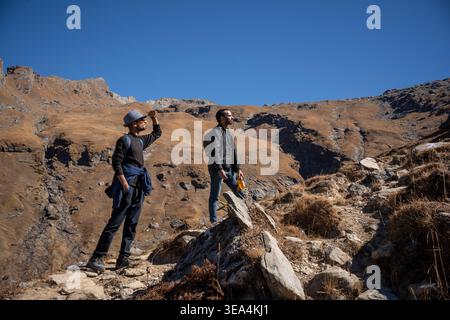 Zwei Wanderer stehen auf einem felsigen Bergpfad und genießen den atemberaubenden Blick auf den klaren blauen Himmel an einem sonnigen Tag während ihrer Wanderung auf dem Tre-See Bhrigu Stockfoto