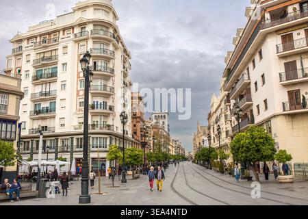 Sevilla, Andalusien, Spanien - 12. Februar 2020: Fußgänger spazieren entlang der Avenida de la Constitucion, einer breiten Straße mit historischen Gebäuden, einem Café im Freien Stockfoto