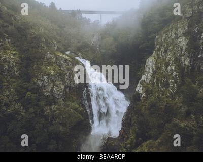 Aus der Vogelperspektive auf den majestätischen Wasserfall Fervenza do Toxa, der durch üppigen grünen Wald und felsige Klippen fällt, Silleda, Pontevedra, Spanien. Stockfoto