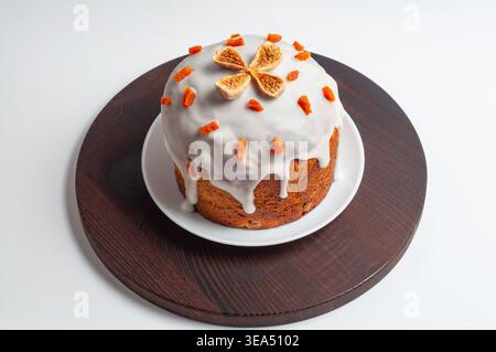 Ein wunderschön dekoriertes Osterbrot, bekannt als Kulich, sitzt auf einem weißen Teller auf einem dunklen Holzbrett, bereit für die Feier Stockfoto