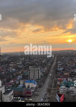 Luftbild bei Sonnenuntergang mit langer gerader Straße, Wohnhäusern und warmem goldenem Himmel, Blick auf die Stadtlandschaft Stockfoto