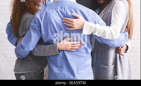 Eine Gruppe divergierende Menschen, die im Kreis stehen und sich gegenseitig umarmen Stockfoto