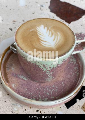 Nahaufnahme von Cappuccino mit Latte Art in Keramikbecher auf strukturiertem Tisch Stockfoto