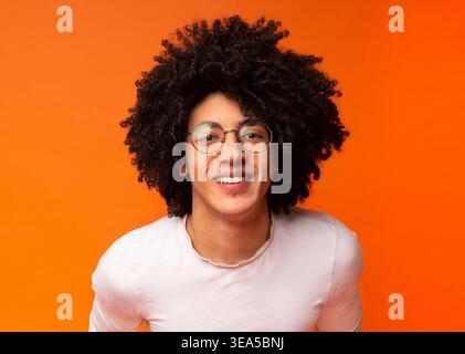 Sorgloser schwarzer buschiger Kerl, der in die Kamera lächelt Stockfoto