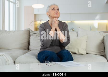 Traurig müde krank krank einsam enttäuscht ältere ältere Frau, die allein zu Hause sitzt. Unglückliche, reife Großmutter erlebt Trauer relativer Tod schlechte Nachrichten. Gestresste ältere Dame, die unter Einsamkeit leidet Stockfoto