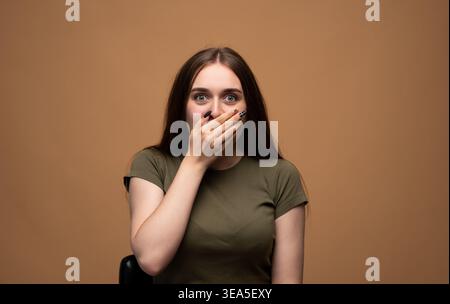 Junge Frau, die den Mund mit der Hand bedeckt, Überraschung, Schock und Unglauben mit weiten Augen und offenem Blick ausdrückt Stockfoto