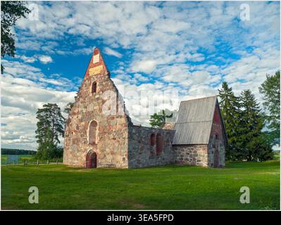 Pälkäne, Finnland - 06.29.2018: Mittelalterliche Ruinen mit roten Ziegelbögen und einem hölzernen Giebeldach, auf einem Grasfeld unter blauem Himmel. Stockfoto