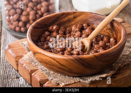 Müsli Schoko Kugeln in Schüssel mit Milch auf rustikalen Holztisch Stockfoto