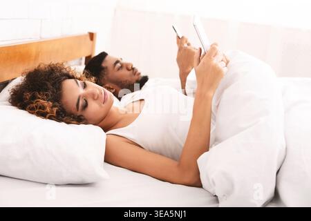 Junges Paar mit Handys arbeiten vom Bett Stockfoto