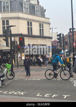 FINCHLEY ROAD U-BAHN STATION ENANCE UND CANFIELD ROAD NORTH LONDON MIT VERKEHR UND RADFAHRERN UND BLICK AUF DIE LINKE STRASSENMARKIERUNG Stockfoto