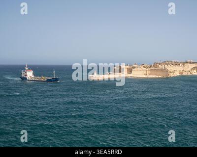 Der Frachter fährt in den Hafen von Valletta Grand, vorbei an Fort Ricasoli und Leuchtturm Stockfoto