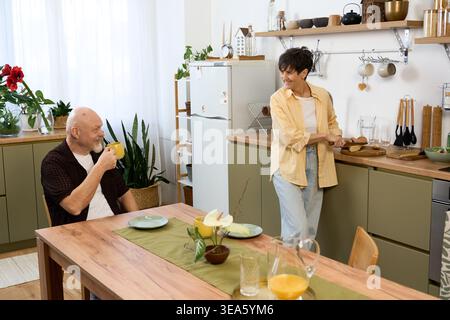 In einer hellen Küche teilt sich ein liebevolles Seniorenpaar mit einem Lächeln und einem Frühstück, das Glück ausstrahlt. Stockfoto