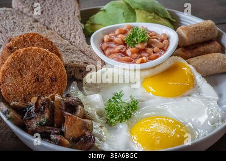 Frühstück mit Spiegeleiern. Schließen Sie ein klassisches traditionelles englisches Frühstück mit sonnigen Beilagen, Eiern, Würstchen, Bohnen, Kartoffelrösti und Avocado. Gesunde Ei Stockfoto