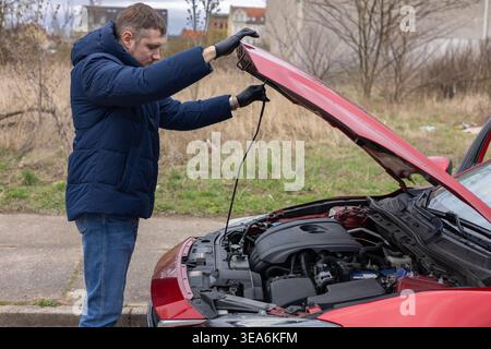 Mann, der den Motor unter geöffneter Motorhaube inspiziert und die Fahrzeugwartung und -Diagnoseprüfung durchführt Stockfoto