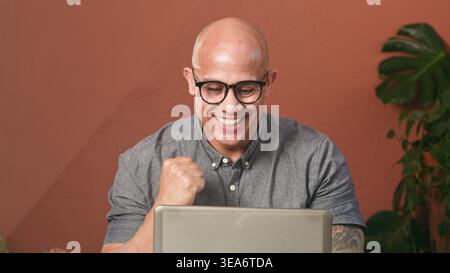 Geschäftsmann feiert Erfolg bei der Arbeit am Laptop im Home Office, Remote Work Victory Stockfoto