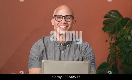 Lächelnder Geschäftsmann, der in ungezwungener Büroumgebung mit Indoor Plant arbeitet Stockfoto