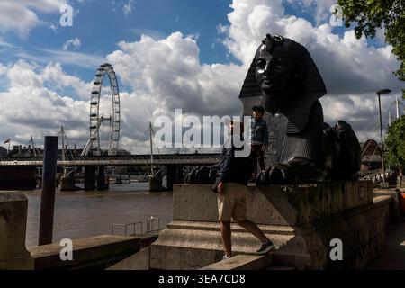 Eine Person spaziert entlang eines Steinpiers in der Nähe des London Eye und der Themse. Stockfoto