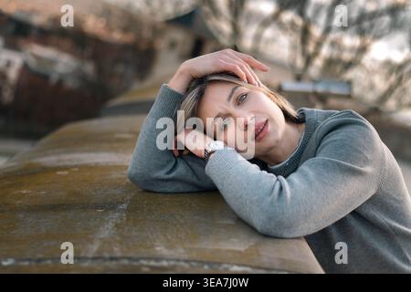 Junge Frau, die ihren Kopf auf den Armen in Soft Outdoor Portrait legt Stockfoto