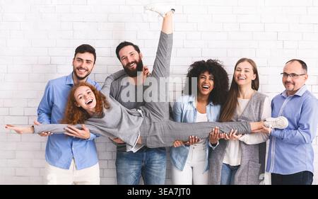Jugend und Spaß. Eine Gruppe verschiedener Leute, die Freunde halten und sich auf weißem Backstein-Wandhintergrund posieren Stockfoto