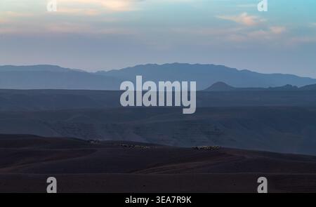 Die mehrschichtigen Silhouetten der Berge lassen sich unter einem ruhigen Abendhimmel in die Ferne eintauchen Stockfoto