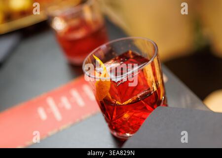 Roter Negroni-Cocktail mit Orangenschale auf dunkler Bartheke Stockfoto