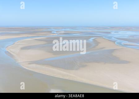 Weite von Gezeitensand und Wattenmeer an der Küste der Normandie unter klarem blauem Himmel im Sommer Stockfoto