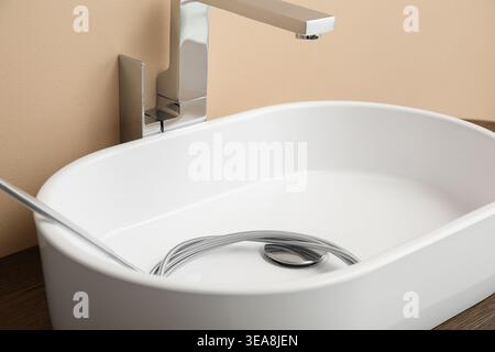 Waschbecken mit verstopftem Abfluss und Klempnerschlange im Bad, Nahaufnahme Stockfoto
