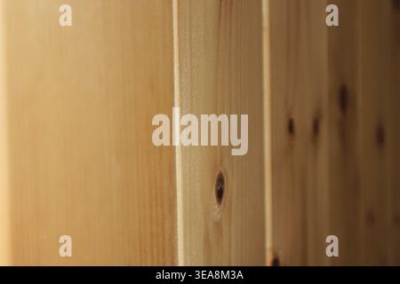 Nahaufnahme von Holzdielen mit Knoten und Linien im Holz. Licht trifft auf die Oberfläche, um die natürliche Körnung hervorzuheben. Die Umgebung ist ein warmes Innenraum A Stockfoto