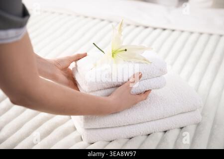 Frau, die Handtücher und Lilienblüten aus dem Bett nimmt, Nahaufnahme Stockfoto