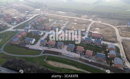 Eine Luftaufnahme eines neu errichteten Wohnviertels mit einheitlichen Häusern, grünen Rasenflächen und umliegendem, unbebautem Land bei Taylor Wimpey in Stockfoto