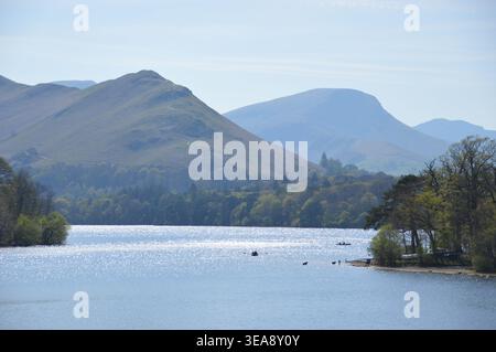 Ruhiges Wasser von Derwent Water im Lake District, Cumbria, England, mit Sonnenschein auf der Oberfläche und Bergen in der Ferne Stockfoto