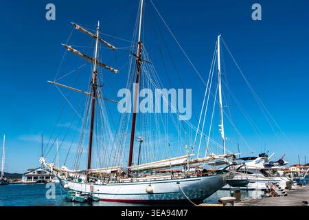 Der Schoner Sir Robert Baden-Powell vertäute an einem Pier in Porto Rotondo, Sardinien, Italien, unter einem klaren blauen Himmel mit Yachten in der Nähe. Stockfoto
